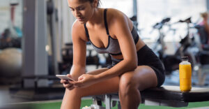 Image of a woman in fitness clothes looking at her cell phone